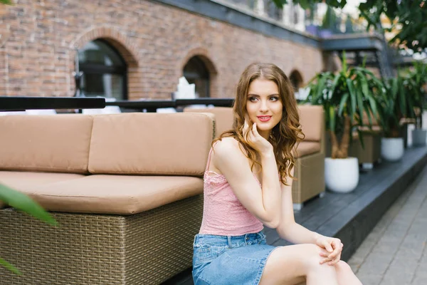 Una bella ragazza romantica in un top rosa e gonna di jeans tiene lui — Foto Stock