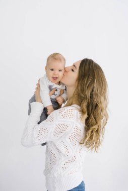 mother holds her five-month-old son in her arms against a light 