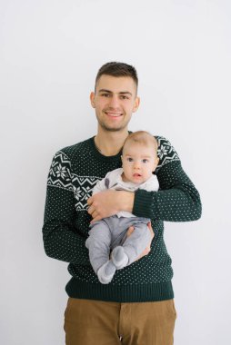 Genç bir baba beş aylık oğlunu kollarında tutuyor. 