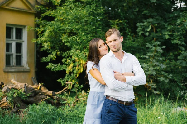 A happy girl hugs her boyfriend from behind and looks at him wit — Stockfoto