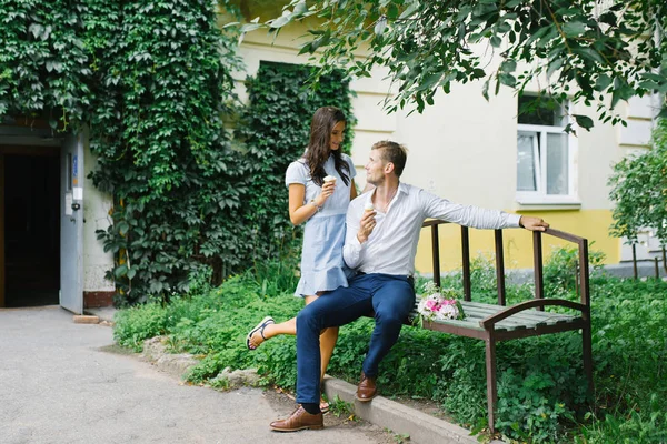 Um belo casal apaixonado, um cara e uma menina sentam-se em um banco e — Fotografia de Stock