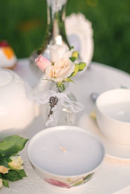 Delicate peach rose flowers in a small glass vase and a candle i