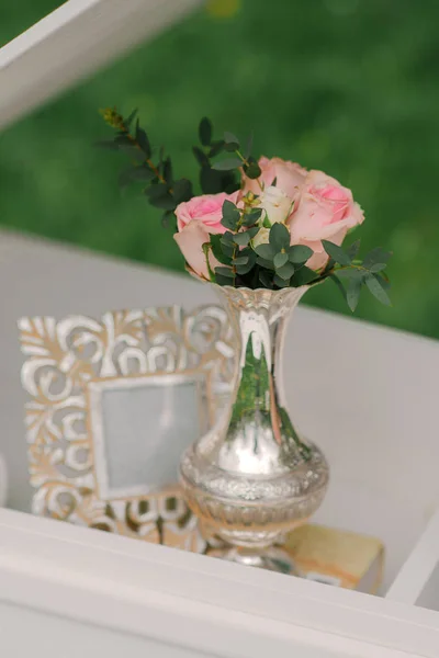 A small silver vase with pink rose flowers and green branches an — Stock Photo, Image