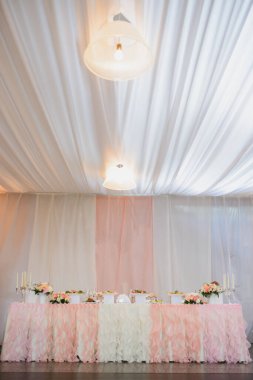 Gelin ve damat için pembe beyaz bir düğün masası.