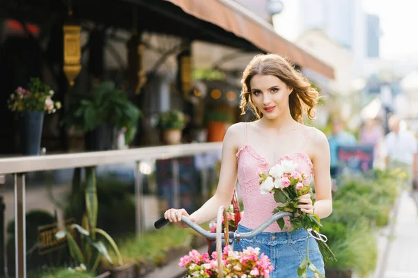 Une belle jeune femme en jupe denim et haut rose marche thro — Photo