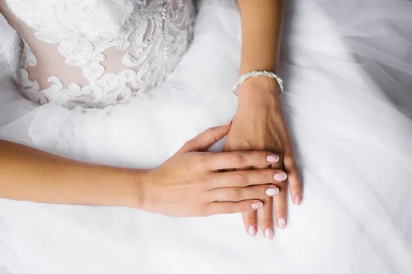 As mãos da noiva estão no vestido branco do casamento, manicu do casamento — Fotografia de Stock