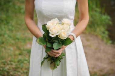 Delicate wedding bouquet of white roses in the hands of the brid