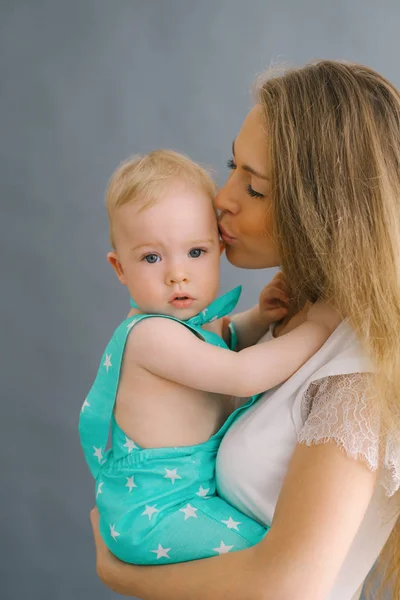 Uma jovem mãe beija o seu lindo filho de um ano. Mãe d — Fotografia de Stock