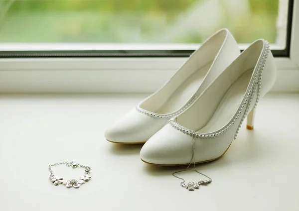 Witte damesschoenen en juwelen liggen op de vensterbank. Accessori — Stockfoto