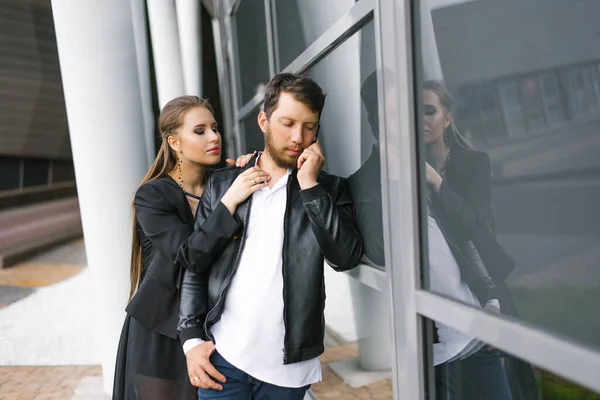 Stylish young guy and girl in black clothes. A man is talking on