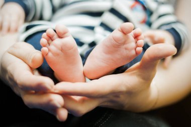 Annesinin elinde küçük bir çocuğun bacakları, yakın plan. Seçici odak.