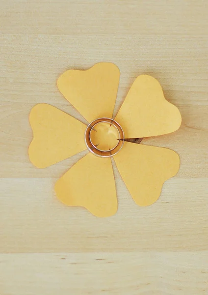 Anéis Casamento Jazem Uma Flor Papel Laranja Fundo Bege Madeira — Fotografia de Stock