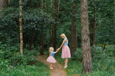 Aynı romantik kıyafetleri giyen bir anne ve beş yaşındaki kızı parkta ya da ormanda yürüyorlar. Anneler Günü.