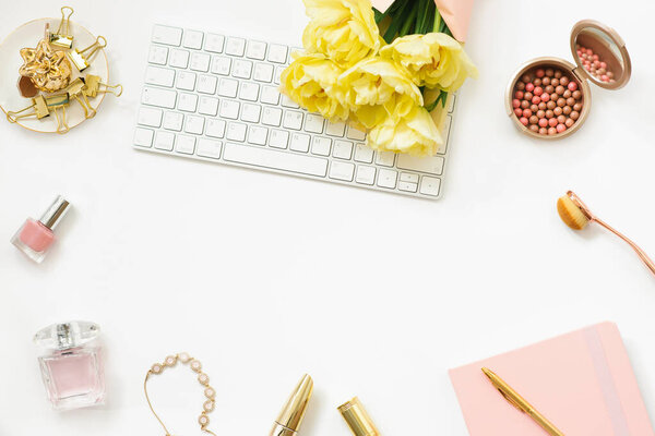 Workplace of a fashion blogger with a bouquet of yellow spring tulips. Flat lay for an online cosmetics store.