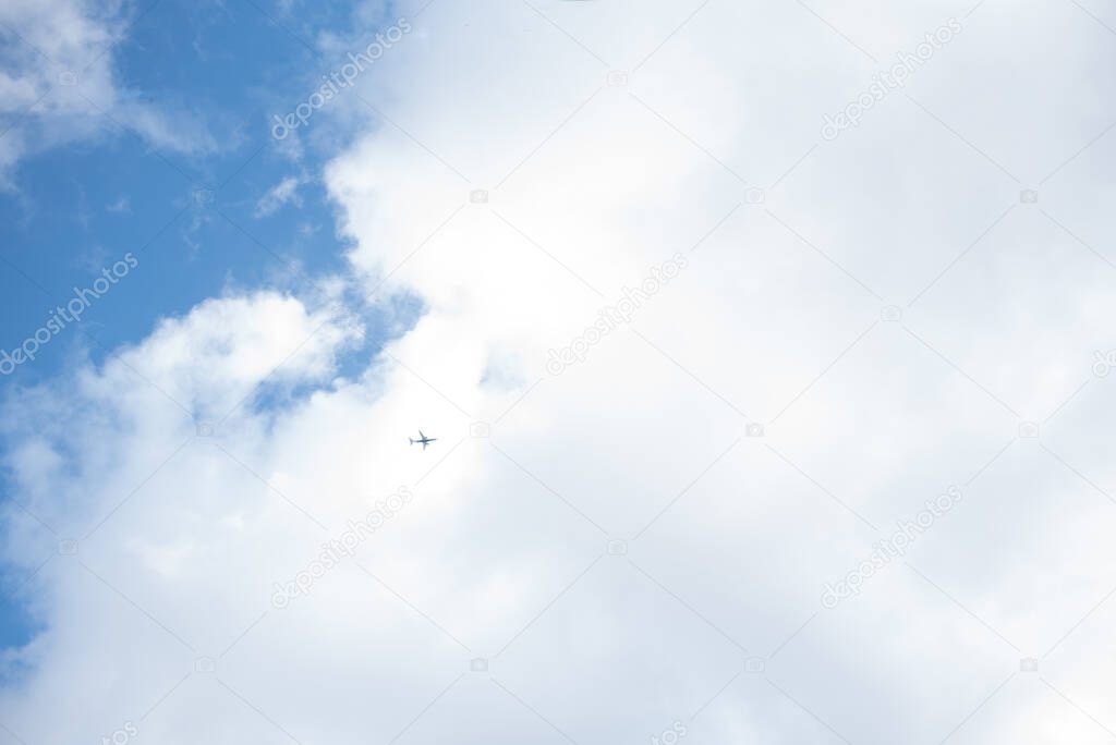 The plane is flying in the sky with clouds