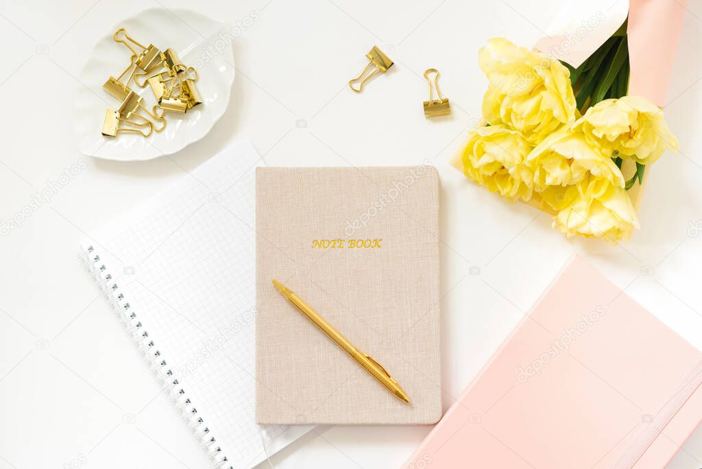 Spring flat lay in pink and yellow tones for a self-employed freelance girl. Work from home. Notebooks and diaries, pen, bouquet of tulips