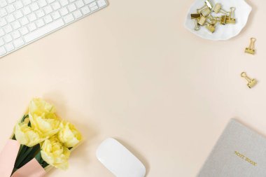 Notepad, klavye ve bir buket sarı şakayıklı lale ile düz uzanan blog yazarı veya bağımsız çalışma alanı