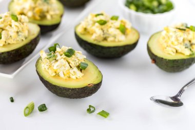 Yumurta salatasıyla doldurulmuş ve yeşil soğanla kaplanmış avokado yarımlarını yakın plan yemeye hazır..