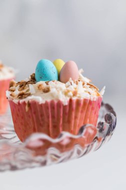 Paskalya için hindistan cevizi kremalı bir kekin ortasındaki üç küçük yumurtadan oluşan bir yuvayı oluşturduğu yakın plan..