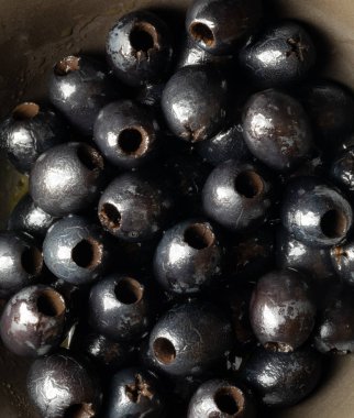 Top down macro close up of a bowl full of black olives ready for eating.