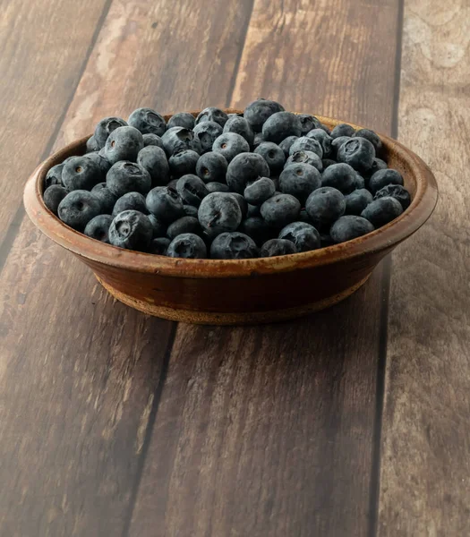 Close up of a bowl of frozen blueberries on a wooden table. — Stock Photo, Image