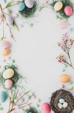 Top down view of an Easter border flat lay including robins eggs, chocolate eggs and nests in desaturated colours.