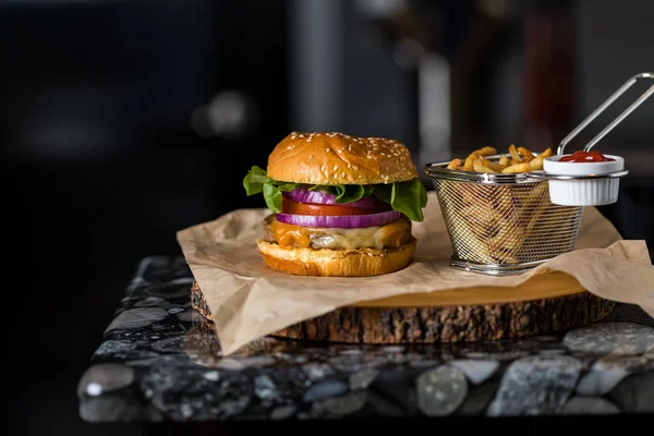 Nahaufnahme eines Cheeseburgers und Pommes vor dunklem Hintergrund — Stockfoto