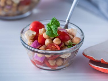 Fesleğenle süslenmiş küçük bir kase nohut salatası..