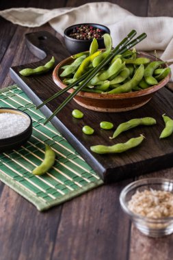 Kapsüllerinde taze organik edamame fasulyeleriyle dolu bir kırsal kasenin yakınında..