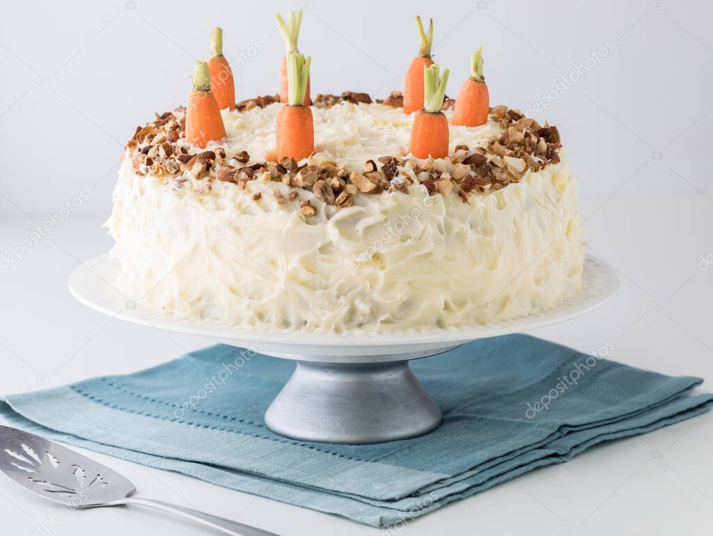 A close up view of a whole decadent carrot cake with cream cheese frosting on a cake stand.