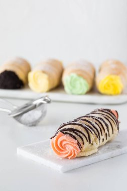 Çilek kremalı cannoli 'nin yakın plan resmi. Çikolata çiselemeli ve diğer cannoli' lerle kaplı.. 