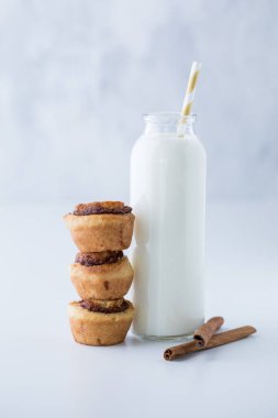 Üç küçük tarçınlı çöreğin yenmeye hazır olduğu bir şişe süt..