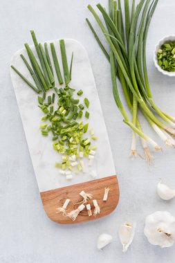 Beyaz mermer kesim tahtasının üzerinde doğranmış yeşil soğanın yukarıdan görünüşü. 