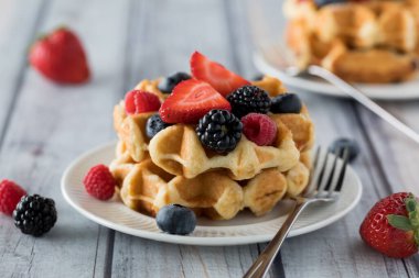 Yemeye hazır çeşitli meyvelerle kaplı bir yığın Belçika waffle 'ının yakın görüntüsü..