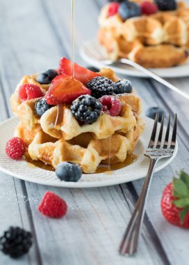 Üzeri böğürtlen, pudra şekeri ve şurupla kaplı Belçika waffleları..