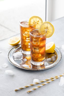 Önünde pipetler olan pencerenin kenarındaki iki buzlu çay bardağını kapat..