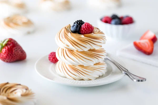 A close up view of a stack of toasted meringues topped with berries ready for eating. — Stock Photo, Image