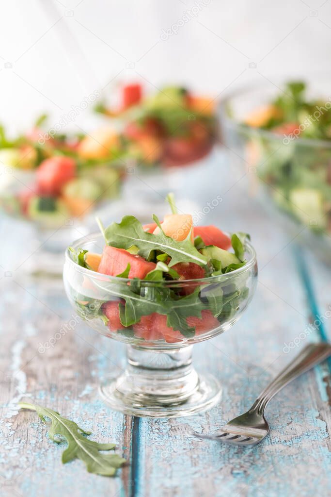 A close up of a glass dish of watermelon salad with other dishes of the same in behind.