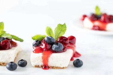 Kirazlı cheesecake meydanının yakın plan görüntüsü ve arkasında da yumuşak odaklı bir diğeri..