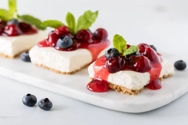 Kiraz soslu, yaban mersinli ve nane şekerli cheesecake karelerinin yakından görüntüsü..