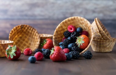 Tahta bir masaya dökülen böğürtlenlerle dolu waffle kâselerinin yakın görüntüsü.