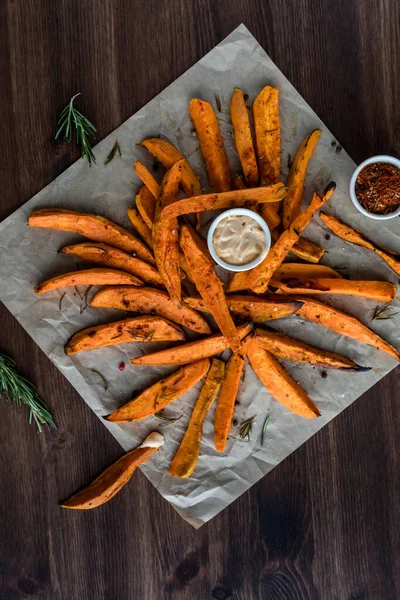A flat lay view of sweet potato fries on parchment paper with dipping sauce and spices. — Stock Photo, Image