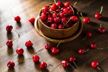 Yan taraftan aydınlatılmış bir kase dolusu kirazı koyu bir arka planda yakından görmek..