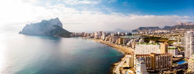 Aerial view of Calpe city in Alicante, Spain, at sunrise. La Fossa beach is in the foreground and de Ifach Penon rock in the background. clipart