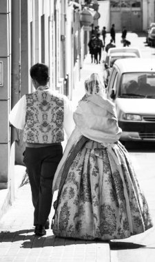 Kimliği belirsiz bir çiftin tipik Fallera elbisesi giymiş siyah beyaz portresi. İspanya 'nın Denia kentindeki ünlü Fallas festivalinde sokakta yürüyorlar..