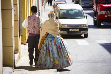 Denia, İspanya - Mart 2019: Tipik Fallera elbisesi giymiş bir çift. İspanya 'nın Denia kentindeki ünlü Fallas festivalinde sokakta yürüyorlar..