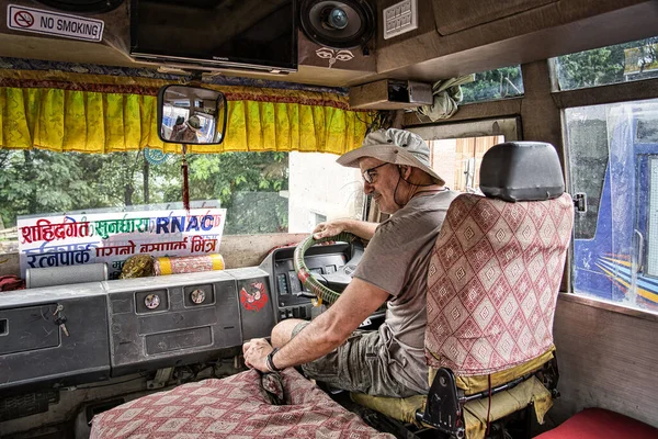 Västra turist med mössa kör en dekorerad lokal buss i Nepal. — Stockfoto