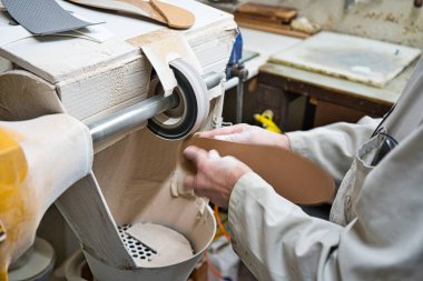 Profesyonel ortopedik taban parlatıcı, zımpara kağıdı torna ile şablonların modellenmesini atölyesinde zımparalama, zımparalama ve kontrol ustası. Ellerin tozla kaplı..