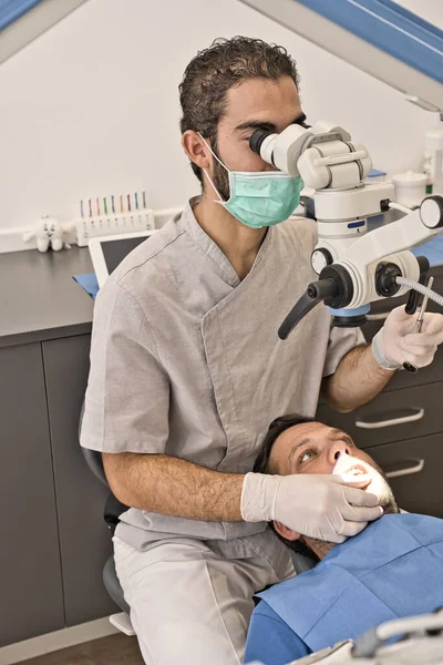 Dental doctor with microscope and hygienic gloves checking the dental health of his patient in a modern clinic — Stock Photo, Image