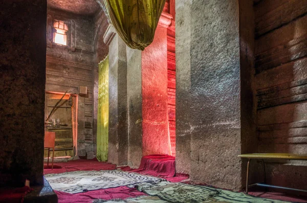 Interior space of a church of Lalibela in Ethiopia without people where the light is colored with the reflection of the color from the curtains of the sparedes.